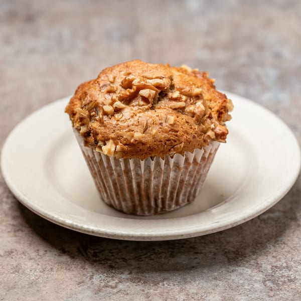 A Pizagel's Bakery muffin with walnuts on a white plate.