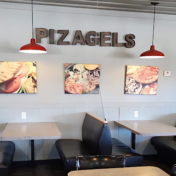 Pizagel's restaurant interior with booths, tables, red pendant lights, and food art on the wall.