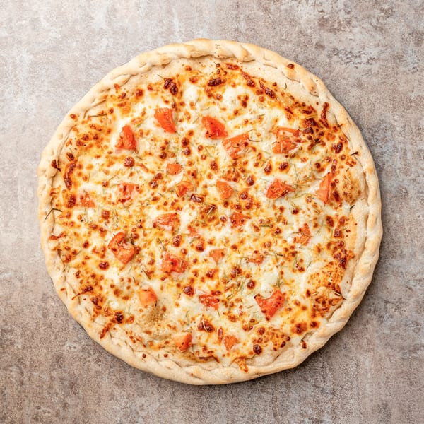 Pizagel's white pizza with melted cheese, diced tomatoes, and herbs on a stone surface.