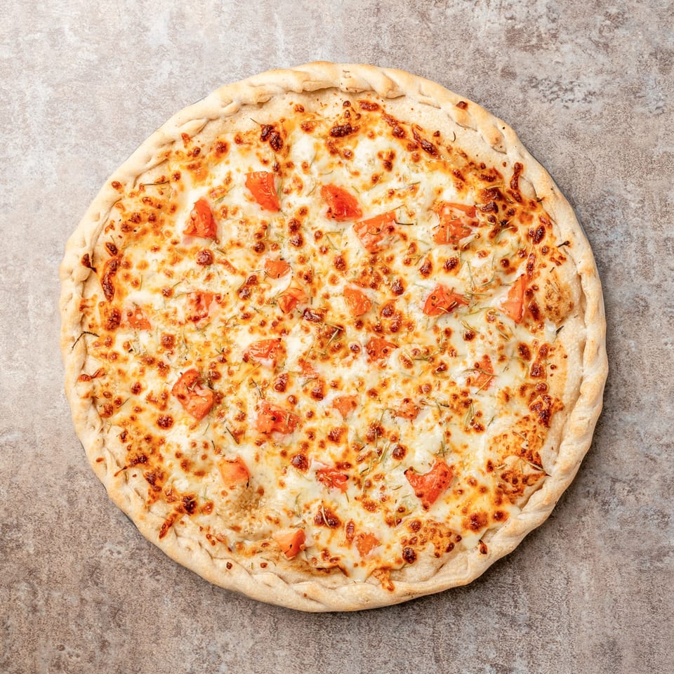 Pizagel's white pizza with melted cheese, diced tomatoes, and herbs on a stone surface.